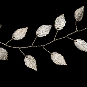 Détail macro du bandeau à feuilles dorées fait main avec texture de vigne sur fond noir uni