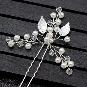 Détail d'épingle à cheveux artisanale avec feuilles argentées et perles pour coiffure mariée