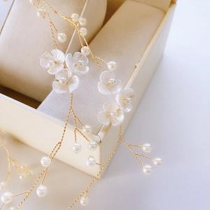 Detail of handmade bridal hair vine with pearl flowers and golden wire accents