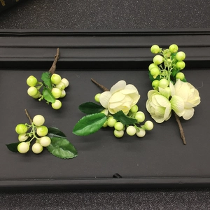 Detailed set of artificial ivory flowers and green berries on a black tray