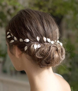 Détail d'une vigne de cheveux argentée avec feuilles ciselées sur un chignon bas de mariée