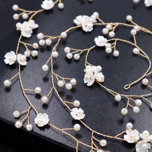 Handmade bridal hair vine with white pearls and gold wire flowers on a black background