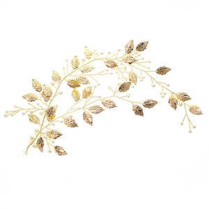 Makroaufnahme von goldenen Metallblättern und weißen Perlen auf Brauthaarschmuck