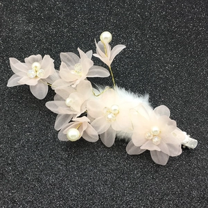 Détail de pince à cheveux avec fleurs en mousseline rose, perles blanches et plumes douces