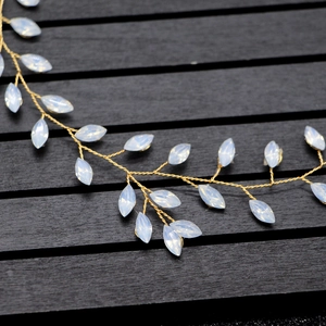 Macro detail of bridal hair vine with golden wires and opal-like marquise leaf stones