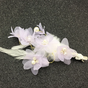 Détail d'une pince à cheveux fleur en mousseline lavande avec plumes et perles