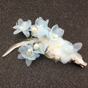 Détail de pince à cheveux fleur en organza bleu clair avec plumes blanches et perles