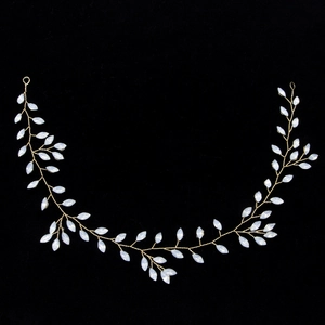 Detail of bridal hair vine with golden wire and opal marquise leaf stones on black background