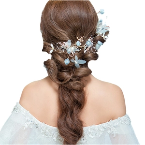 Detailed bridal hairpiece with light blue flowers and pearls on a white background