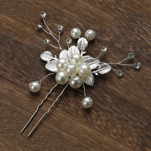 Détail d'épingle à cheveux argentée avec feuilles, perles blanches et strass brillants