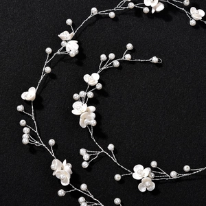 Macro detail of handmade silver wire hair vine with white flowers and pearls for brides