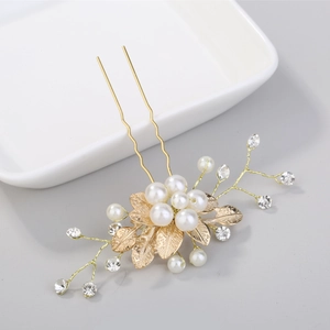 Détail d'épingle à cheveux feuille dorée avec perles blanches et strass brillants