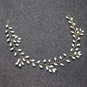 Detailed macro view of bridal hair vine with golden wire and white leaf stones