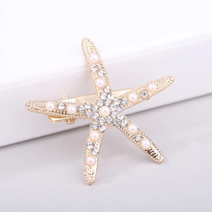 Detail of starfish hair clip with white pearls and sparkling crystals on golden metal base