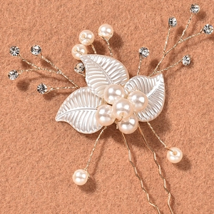 Détail de l'épingle de mariée avec feuilles en résine blanche, perles et cristaux sur épingle dorée