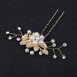 Vue macro détaillée des feuilles en métal doré et perles blanches sur l'épingle à cheveux en U