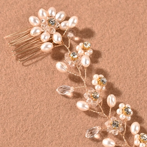 Gros plan du peigne à cheveux de mariée doré avec perles blanches et fleurs de cristal