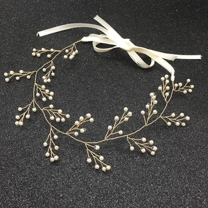Dettaglio della fascia con perle in filo metallico dorato e nastro in raso bianco fissato