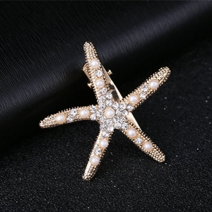 Close-up of golden starfish hair clip with sparkling rhinestones and white pearls detail