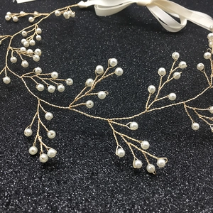 Dettaglio macro della fascia da sposa dorata con perle e nastri di seta bianca