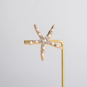 Macro shot of bridal starfish hair clip featuring champagne gold alloy and inlaid pearls