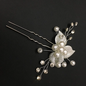 Détail d'épingle à cheveux argentée pour mariée avec perles, cristaux et feuilles en métal