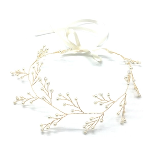 Dettaglio di un cerchietto da sposa in filo dorato con perle e lunghi nastri di raso bianco
