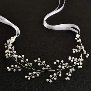 Dettaglio di tralcio per capelli da sposa argento con perle e nastro bianco su sfondo nero