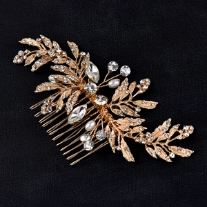 Macro shot of gold leaf bridal hair comb with rhinestones and white pearls on black texture