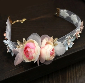 Détail d'un ras du cou floral avec roses en tissu rose, feuilles dorées et perles