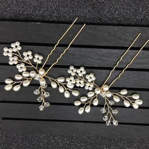 Détail de deux épingles à cheveux de mariée dorées avec perles et cristaux brillants