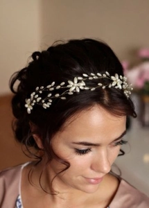 Detailed bridal hairpiece with cream pearls and gold wire on model's dark curly hair
