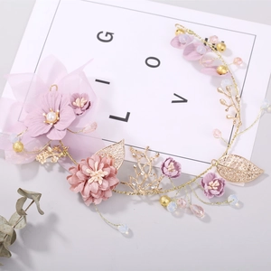 Detailed close-up of bridal headpiece with gold leaves, purple flowers and pearls