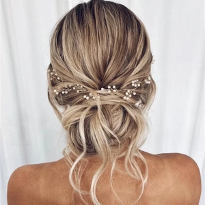Elegante tralcio per capelli da sposa dorato con perle su uno chignon basso