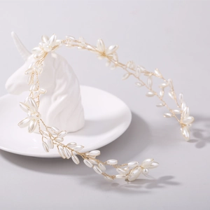 Close-up of handmade bridal hairband with elegant white pearls and golden vine details