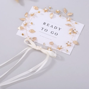 Détail du bandeau de mariée à feuilles dorées avec perles, cristaux et ruban blanc