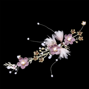 Detailed macro view of purple fabric flowers and golden leaf branches bridal hair accessory