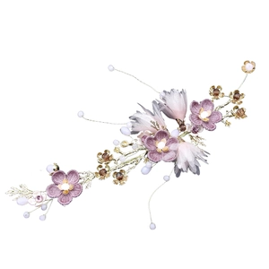Detail of handmade bridal headpiece with purple petals, gold leaves and pearls