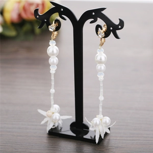 Detail view of long tassel bridal earrings with white pearls and flower petal accents
