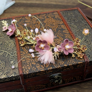 Detail of handmade bridal headpiece with purple fabric flowers and golden leaf branches