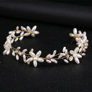 Elegant gold bridal hair vine with white pearl flowers on a dark background