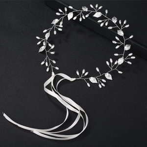 Détail macro du bandeau de mariée avec feuilles argentées, perles et rubans satin