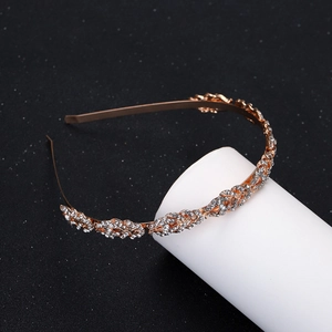 Détail d'un serre-tête doré avec feuilles et strass sur fond noir texturé