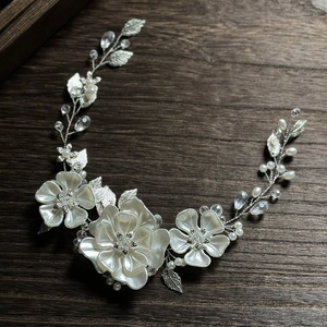 Détail de vigne de cheveux de mariée avec fleurs en perles blanches et cristaux sur bois