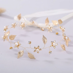 Détail macro du bandeau de mariée en feuilles dorées avec perles blanches et strass