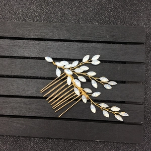Détail d'un peigne à cheveux de mariée en fil doré avec d'élégantes perles de feuilles blanches