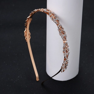 Détail d'un serre-tête doré en forme de feuille avec strass brillants sur fond noir élégant