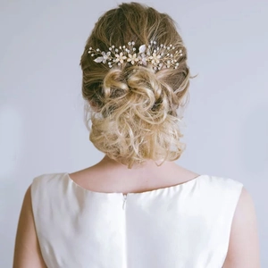 Peigne à cheveux de mariée avec fleurs blanches et perles porté sur un chignon