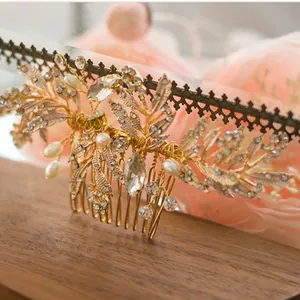 Close-up of golden leaf bridal hair comb with pearls and rhinestones on wood background