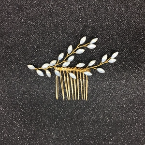 Détail du peigne de mariée doré avec perles marquises blanches sur fond noir brillant